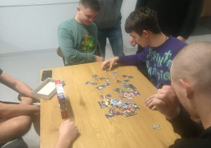 Siedmiu wychowanków siedzi przy stole z puzzlami