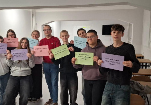W świetlicy cztery wychowanki, wychowawca i czterech wychowanków trzyma kartki promujące bursę