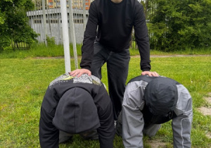 Trzech chłopców tworzących piramidę- jeden na górze, dwóch na dole
