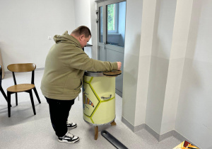Mieszkaniec DPS kręci zabytkową miodarką.