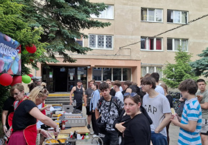 Kilkanaście osób dziewcząt i chłopców stojących w kolejce do degustacji.