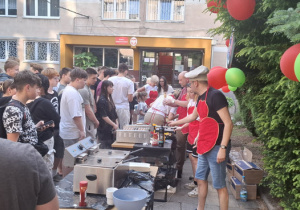 Kilkanaście osób dziewcząt i chłopców stojących w kolejce do degustacji.