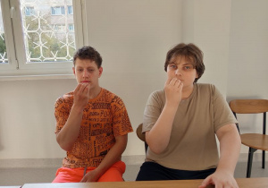 Wychowankowie siedzą przy stole pokazują znak - jeść