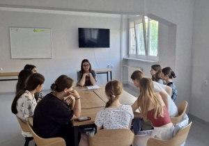 Wychowanki siedzą przy stole i dyskutują na temat zagrożeń podczas wakacji.