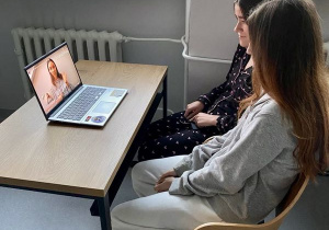 Dziewczynki oglądają film instruktażowy ze znakami języka migowego.