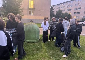 Grupa chłopców stoi przy pojemnikach do segregacji śmieci