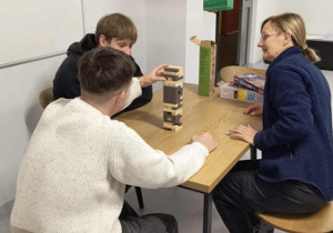 Dwóch wychowanków wraz z wychowawczynią grają w grę planszową Yenga.