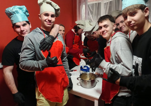 Wychowankowie stoją obok stołu, z przygotowanych produktów zagniatają ciasto.