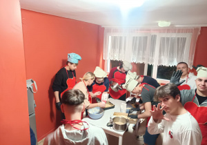 Wychowankowie stoją obok stołu, z przygotowanych produktów zagniatają ciasto.