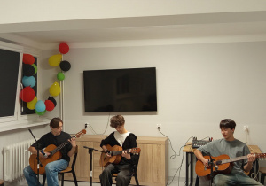 Trzech chłopców gra na gitarze