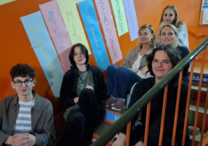 Czworo wychowanków i dwie panie wychowaczynie siedzą na schodach.