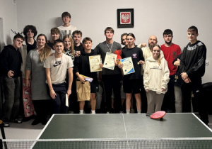 Za stołem tenisowym grupa wychowanków wraz z wychowankami pozuje do zdjęcia