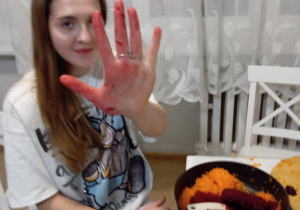 Jena dziewczynka siedzi przy stole i uciera buraki.