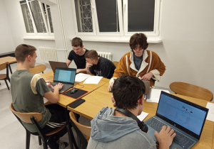 Wychowankowie siedzą przy stole czytają instrukcję tworzenia CV