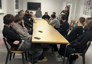 14 wychowanków siedzi przy stole i wraz z wychowawczyniami rozmawiali o Prawach Dziecka.