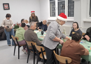 Kilku mieszkańców DPS słucha instruktażu jak wykonać bombki