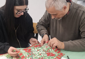 Dziewczynka pomaga wyciąć serwetkę starszemu mężczyźnie