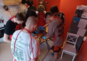 Wychowankowie stoją przy stole- przygotowanie posiłku.