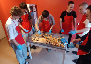 Wychowankowie stoją przy stole- przygotowanie posiłku.