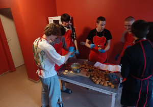 Wychowankowie stoją przy stole- przygotowanie posiłku.