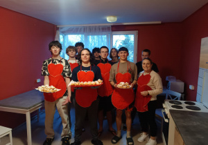 Dziewięcioro wychowanków stoi, troje trzyma przygotowane ptysie.