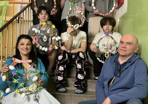 Chłopcy siedzą i stoją na schodach prezentując gotowe wianki wielkanocne