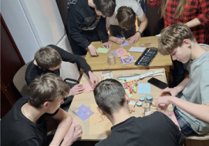 Sześciu wychowanków wraz z wychowawcą wykonuje prace plastyczne z wykorzystaniem różnych materiałów .