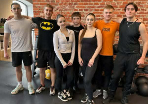 Siedmioro wychowanków stoi pod ścianą i pozują do zdjęcia