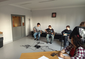 Chłopcy siedzą i grając na gitarach