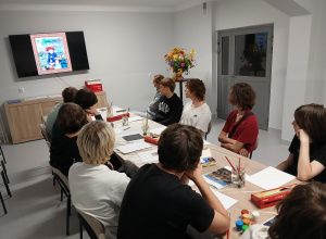 Wychowankowie słuchają programu edukacyjnego na temat malarza Renoir.
